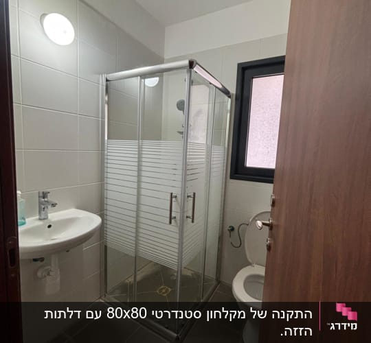מקלחון זכוכית עם כיור ואסלה בחדר אמבטיה